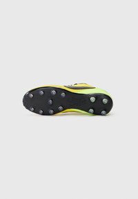 Botín de fútbol con suela negra, parte superior en amarillo y verde, múltiples tacos para tracción, con un diseño texturizado y cierre con cordones.
