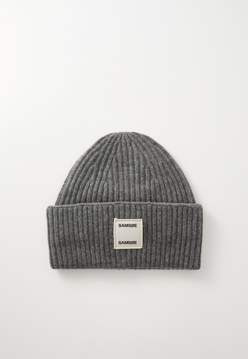 Bonnet tricoté gris avec des côtes verticales, portant une étiquette rectangulaire crème avec "SAMSOE" en texte noir. Texture douce.