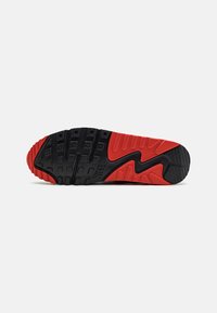Suola di scarpa Nike con una combinazione di colori nero e rosso. Presenta una gomma testurizzata con motivi in rilievo per presa e flessibilità.
