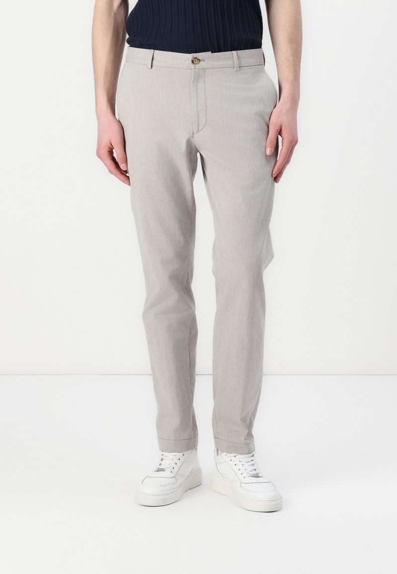 Light grey tailored trousers made from smooth fabric, featuring a front button closure, slim fit, and pockets, paired with white sneakers.