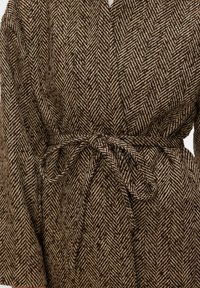 Brūns un bēšs rīveņu zābaku raksta mētelis ar jostu viduklī, izgatavots no teksturēta auduma, ar plašām piedurknēm un atslābinātu piegriezumu.