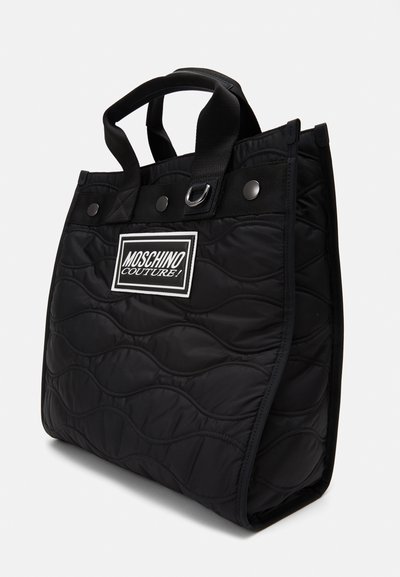 Borsa tote nera trapuntata con un motivo a onde testurizzato, dotata di manici in tessuto duali e una patch con logo sul fronte. Progettata in una forma strutturata.