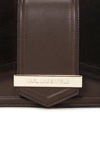 Bruine leren tas met een suède paneel, goudkleurige hardware en een opvallende plaat met "KARL LAGERFELD" erin geperst.