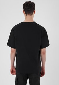 Schwarzes T-Shirt mit kurzen Ärmeln und Rundhalsauschnitt, aus weicher Baumwolle. Hat einen geraden Schnitt und ein minimalistisches Design, ohne sichtbare Muster.