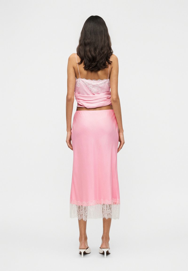 Robe nuisette en satin rose avec bordure en dentelle, dotée de fines bretelles et d'une coupe d écontractée. La jupe est légèrement plus longue avec des accents en dentelle transparente à l'ourlet.