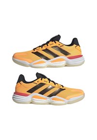 Paire de chaussures de sport basses en mesh orange avec des rayures noires, des lacets noirs, des semelles rembourrées blanches et rouges, présentées en vue latérale.