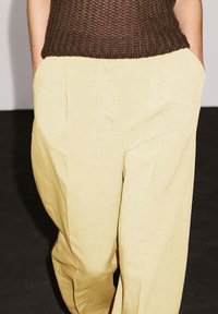 Linnen, lichtgele wijde broek met een gestructureerd oppervlak, voorzien van zijzakken en een ontspannen pasvorm, aangevuld met een bruine, gebreide top.