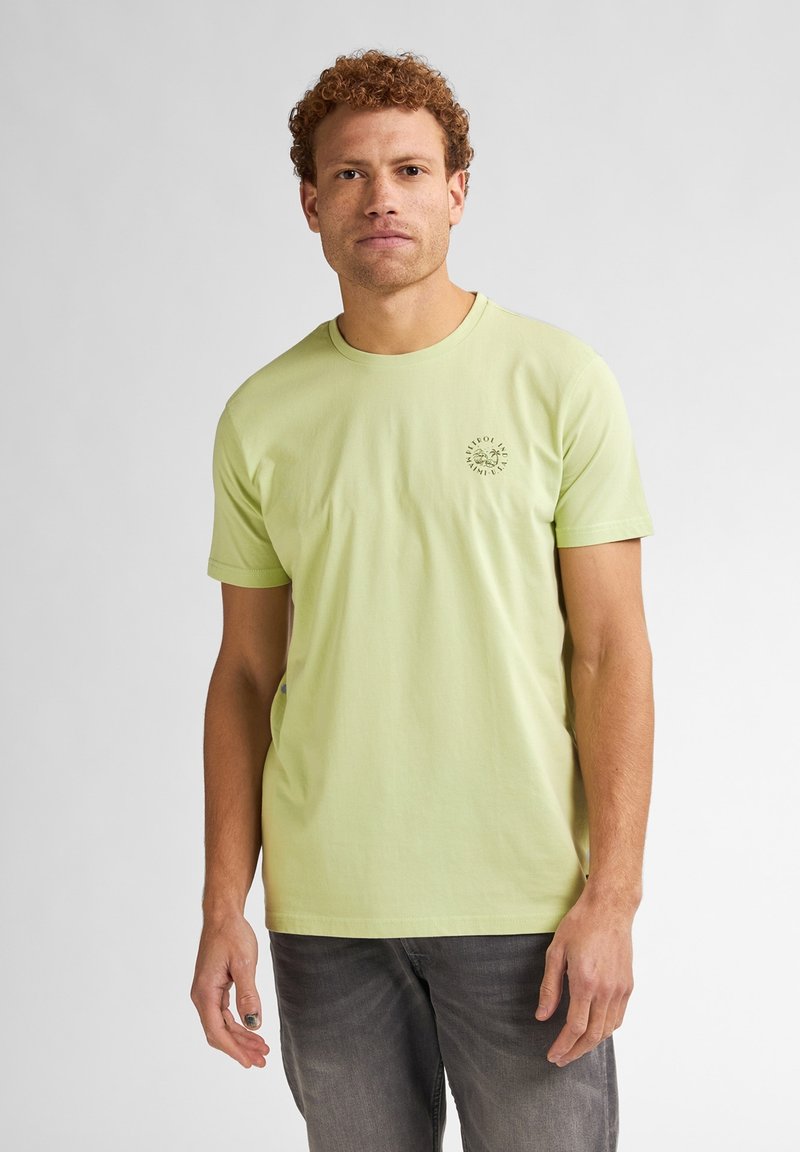 T-shirt di cotone verde chiaro con colletto rotondo e maniche corte. Presenta un piccolo logo circolare stampato sul lato sinistro del petto.