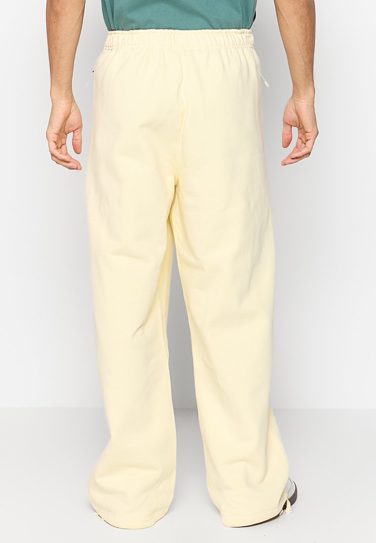 Pantalones sueltos de color amarillo claro con cintura elástica, hechos de una tela suave, con un diseño de pierna recta y sin patrones visibles.