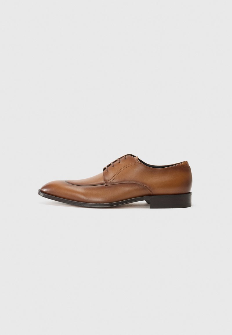 Zapato de vestir de cuero marrón con punta afilada, cierre de cordones y una textura suave. Presenta un tacón bajo y detalles de costura sutiles.