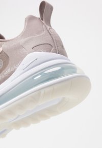 Light beige athletic shoe with suede and synthetic upper, featuring a transparent air cushion sole and white rubber outsole.