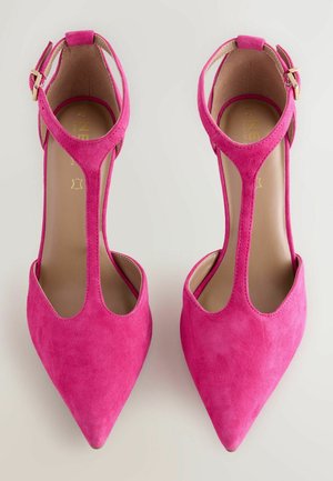 Scarpe con tacco alto in suede rosa con design a punta e cinturino alla caviglia. Presentano lati con intagli e una punta bassa. Accenti in oro.