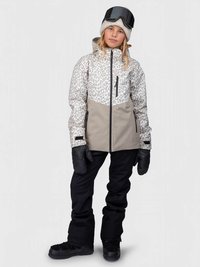 Kind in Leopardenmuster und beiger Skijacke, schwarzen Schneehosen, schwarzen Handschuhen, beigem Mütze und Skibrille auf dem Kopf, steht.