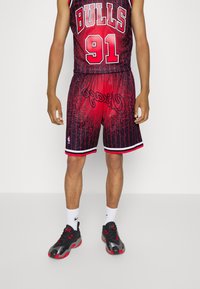 Maillot de basket-ball rouge et noir avec des rayures, arborant les lettres "BULLS" et "91", associé à des baskets noires et des chaussettes blanches.