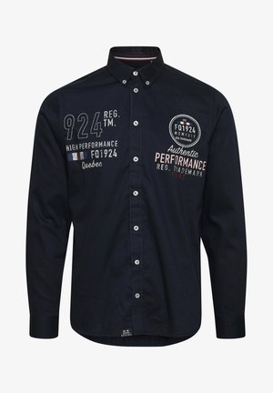 Sötét tengerészkék, gombos póló pamutból. Fehér és színes hímzett felirattal, klasszikus gallérral és ezüst gombokkal az elülső részen.