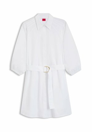 Biała sukienka koszulowa do kolan z długimi bufkami na rękawach, ostrym kołnierzem i materiałowym paskiem z złotą klamrą w kształcie litery D.