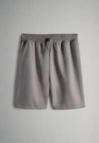 Pantaloni sportivi grigi realizzati in tessuto liscio, con vita elastica e coulisse, e una vestibilità ampia.