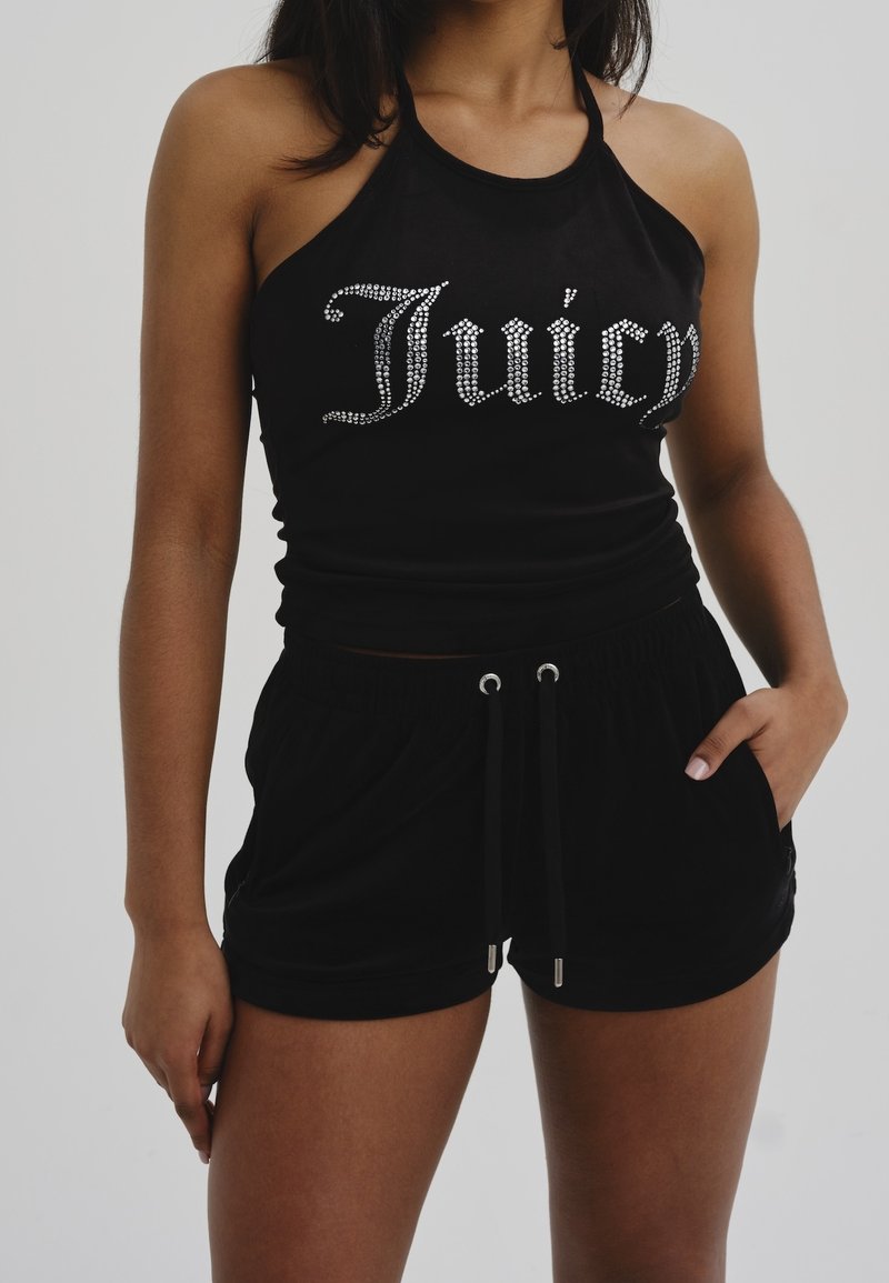 Svart halternecktopp med silverfärgade rhinestone-ordet "Juicy" och matchande svarta shorts med dragsko i midjan och sidofickor. Mjukt tyg.
