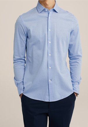 Light blue long-sleeve shirt with a pointed collar, buttoned front, and rounded hem. Made of a smooth, slightly textured fabric.