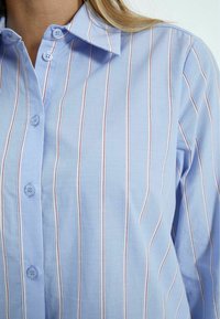 Camicia button-up azzurro chiaro con strisce verticali bianche e rosse, colletto a punta e tessuto di cotone liscio.