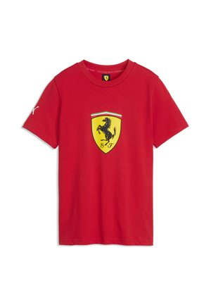 Punainen lyhythihainen t-paita, jossa keltainen Ferrari-logo ja musta pystyssä hyppivä hevonen edessä sekä pieni valkoinen Puma-logo vasemmassa hihassa.