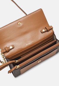 Borsa a tracolla in pelle marrone con più scomparti per carte, una tasca con zip, chiusura a pulsante dorato e logo "Michael Kors" all'interno del patta.