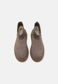Paire de bottines à enfiler en daim taupe avec semelles en caoutchouc marron et doublure en polaire, vue de dessus sur fond blanc.