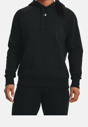 Osoba nosząca czarną bluzę z kapturem Under Armour z przednią kieszenią i sznurkami, widoczna od ramion do bioder na białym tle.