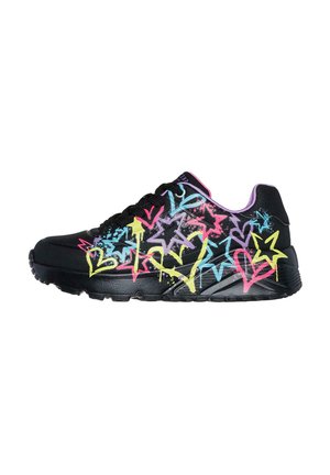 Zapatilla negra con un patrón de graffiti de estrellas coloridas en rosa, azul y amarillo. Presenta una suela resistente y cordones negros.