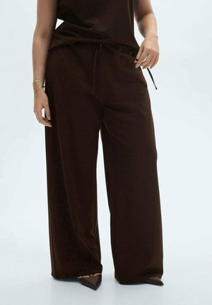 Brown wide-leg trousers in soft fabric, featuring an elastic waistband with drawstrings. Paired with pointed-toe shoes.