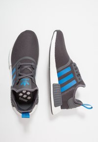 Grå nät sneakers med blå detaljer, featuring en vadderad vit sula, snörningsdesign och en liten hälflik. "Boost"-logotyp synlig inuti.
