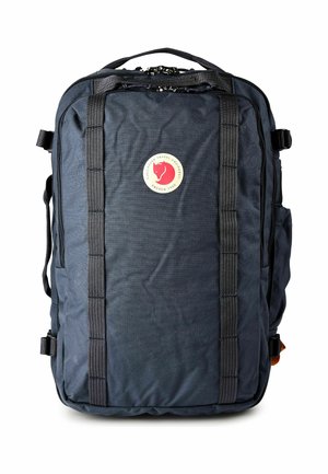 Sac à dos rectangulaire bleu foncé avec double sangle verticale, poignée supérieure, poches latérales et logo circulaire rouge et blanc Fjällräven à l'avant.