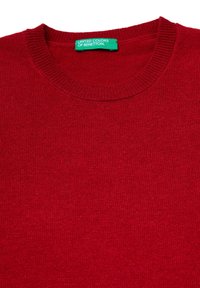 Maglione rosso lavorato a maglia con colletto rotondo a coste. L'etichetta recita "United Colors of Benetton", indicante l'identità del marchio e le istruzioni per la cura.