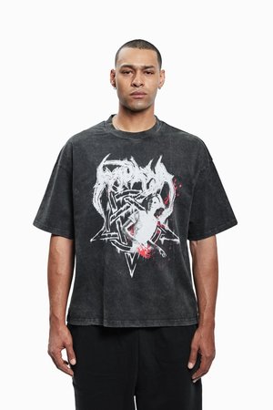 Melnā pārāk liela T-krekla izgatavota no kokvilnas, ar baltu grafikas dizainu sarkanām akcentiem. Īsas piedurknes un apaļa kakla izgriezuma dizains.