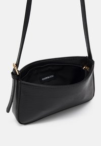Borsa nera con un esterno testurizzato a motivo coccodrillo. Dotata di una lunga tracolla e di un'etichetta interna con marchio. Include una tasca con zip.