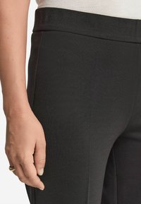 Svarta byxor med en slät textur och skräddarsydd passform. Med hög midja och utan synlig hårdvara eller mönster.