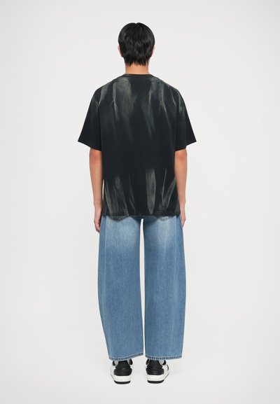 Must mustriba mustelokk, puuvillane kude, mugav lõige; koos laia lõikega helesiniste denim teksadega, lõpetatud kulunud äärtega.