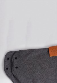 Gray felt product with rounded edges, featuring two black snaps and a brown leather tag with etchings. Textured surface, minimalist design.