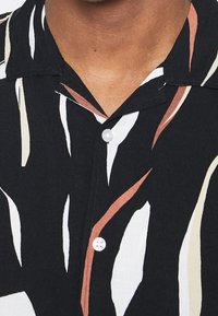 Overhemd met knopen, zwarte basis, met abstracte, gebogen lijnen in crème, bruin en wit. Lichtgewicht stof met een klassieke kraag.