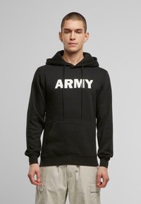 Fekete kapucnis pulóver, pamutból készült, nagy fehér betűkkel „ARMY” felirattal. Kenguru zsebbel és állítható húzózsinórral ellátott kapucnival rendelkezik.