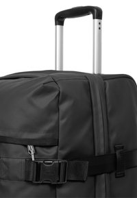 Schwarzer rollbarer Koffer aus strapazierfähigem Stoff, mit verstellbarem Teleskopgriff, Reißverschlusstasche und Schnallenverschluss für sichere Aufbewahrung.