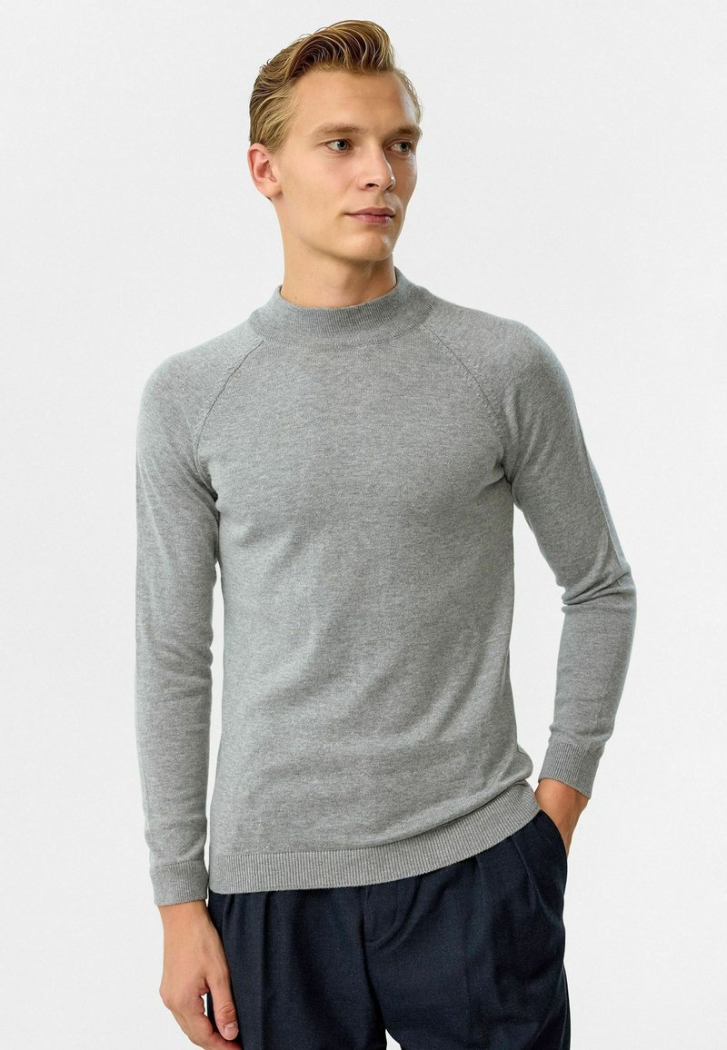 Grau gestrickter Pullover mit einem hohen Kragen, langen Ärmeln und gerippten Bündchen und Saum. Geschmeidige Textur, figurbetontes Design und Raglanärmelkonstruktion.