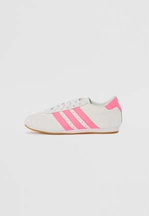 Vita atletiska skor med rosa accenter och tre rosa ränder på sidan, med en texturerad ovandel och gummisula.