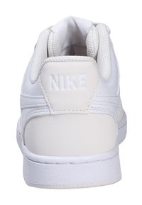 Sneaker Nike bianche con tomaia in pelle liscia, colletto imbottito e logo in rilievo sul tallone. Suola spessa in gomma con motivo testurizzato.