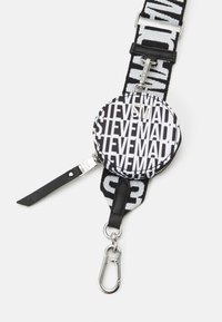 Sangle réglable noire et blanche avec texte répétitif et une pochette ronde zippée attachée, comprenant un mousqueton métallique à une extrémité.