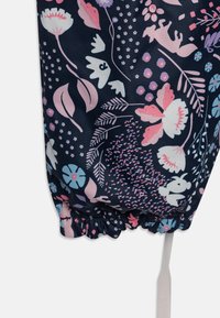 Bloemmotief stof met roze, blauwe en witte bloemen op een donker marineblauwe achtergrond. Geraamde elastische zoom met een witte trekkoord.