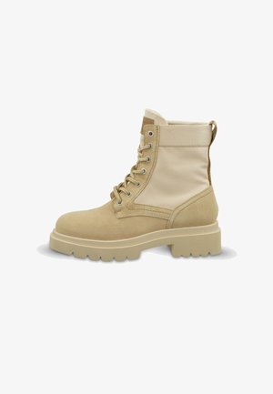Beige Schnürstiefel mit dicker Gummisohle, Wildleder an Zehen und Ferse, Obermaterial aus Stoff und Zugschlaufe hinten.