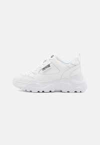 Baskets blanches chunky avec une semelle en caoutchouc texturé, un dessus en cuir et des détails perforés. Présente un logo sur le côté et une languette à l'arrière.