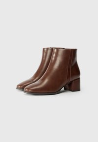 Brown leather ankle boots with a smooth texture, pointed toe, and a square block heel. Side zipper closure visible on each boot.