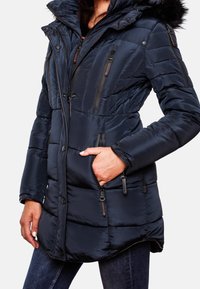 Mörkblå vadderad jacka med pälsfodrad huva, flera fickor med dragkedjor, slät textur och skräddarsydd passform för värme.